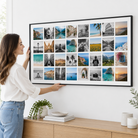 Vrouw hangt de Instawall Canvas Wide fotocanvas met zwarte baklijst op aan de muur